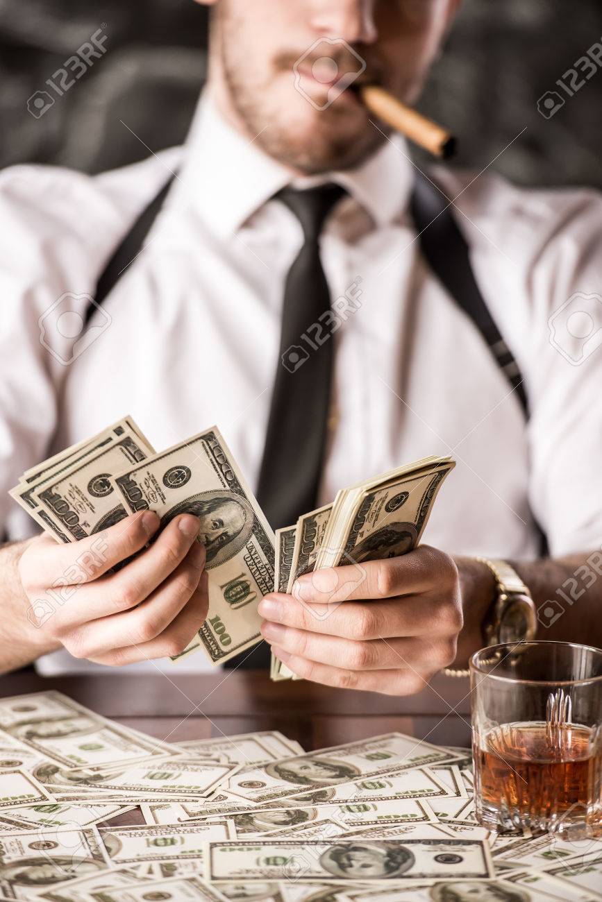 36818231-gangster-in-shirt-and-suspenders-is-counting-money-and-smoking-cuban-cigar-while-sitt...jpg