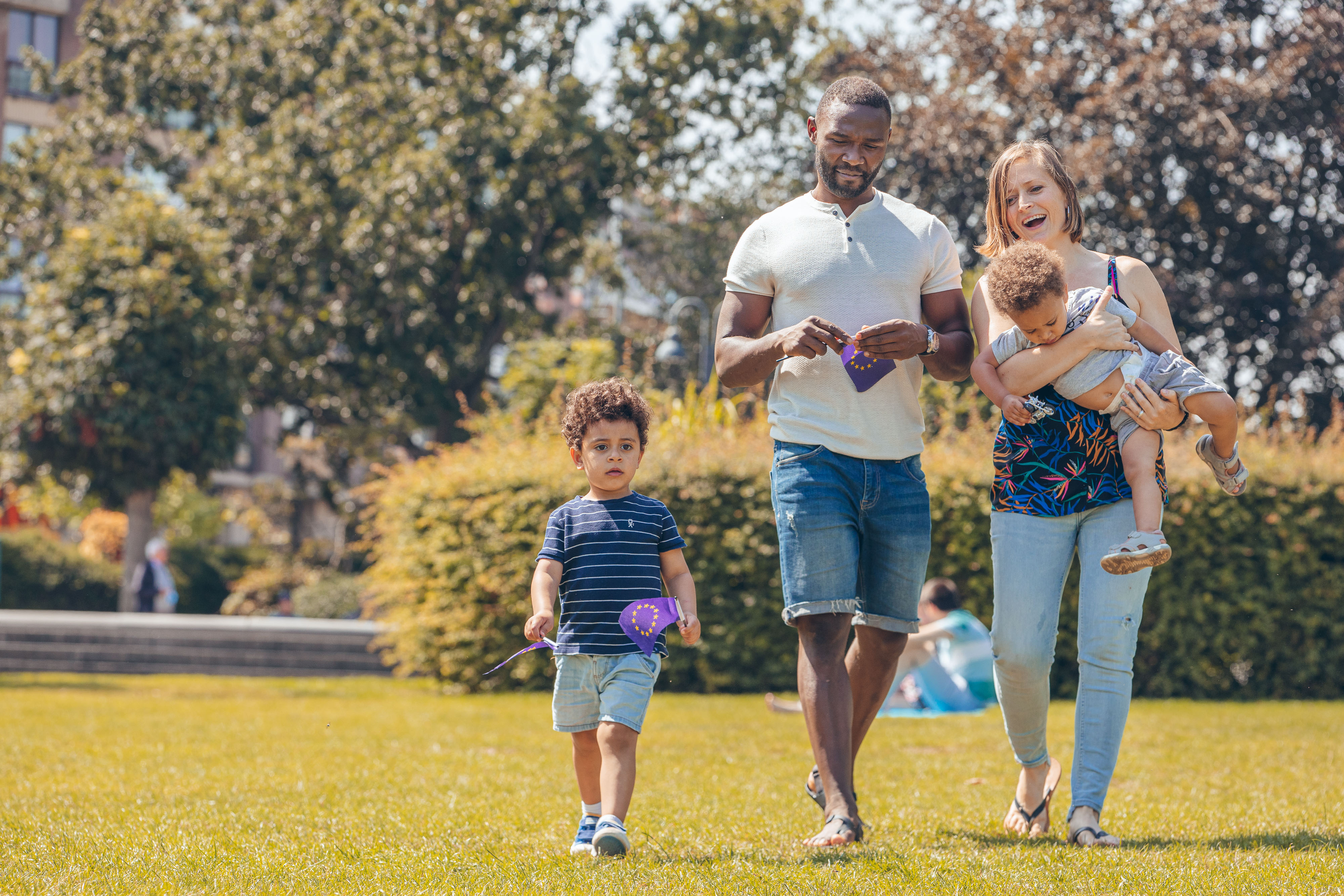 A_mixed-race_family_walking_in_a_park_with_European_flags_(P044728-798775).jpg