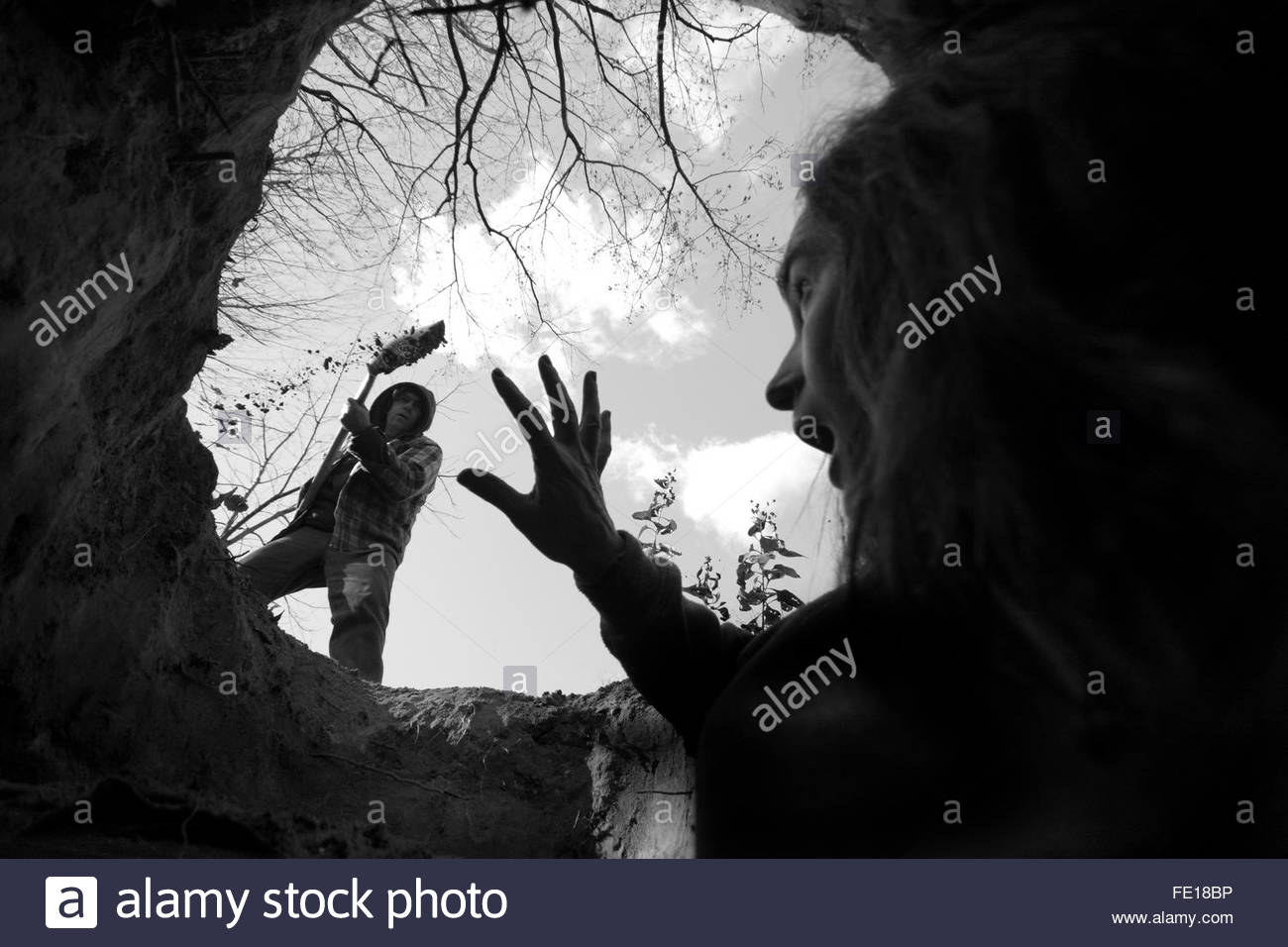 woman-being-buried-alive-by-man-shovelling-dirt-bw-black-and-white-FE18BP.jpg