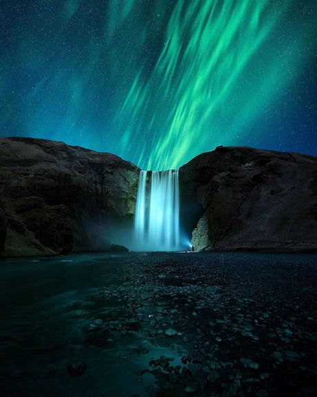 Aurora Borealis painted behind a glowing waterfall in Iceland