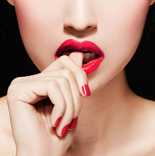 closeup-of-woman-biting-nails-or-fingersred-lips-and-manicure-picture-id501667346
