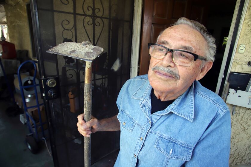 Fausto Rios, 82, of Colton, who worked as a bracero or farm worker for most of his life, poses with a type of hoe a farm worker would use, he pose for a picture at his home in Colton on Monday, June 13, 2022. Rios now wants to play a role in exposing and ending the long history of the mistreatment of hispanic farm workers.