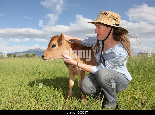 young-farmer-woman-with-little-baby-cow-in-grassy-field-c0523t.jpg