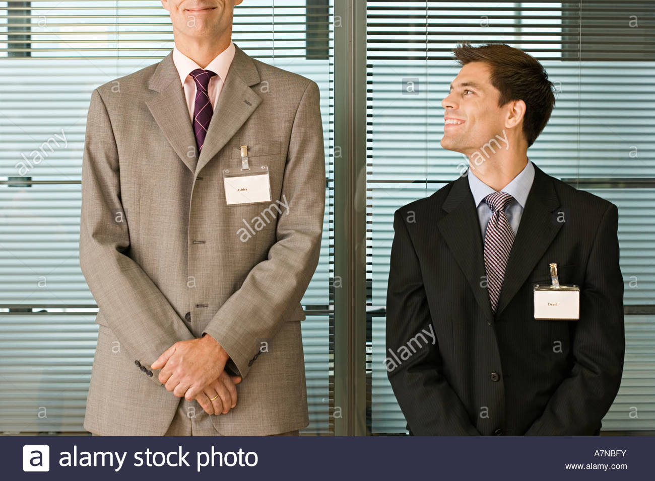 short-businessman-looking-up-at-tall-businessman-standing-side-by-A7NBFY.jpg