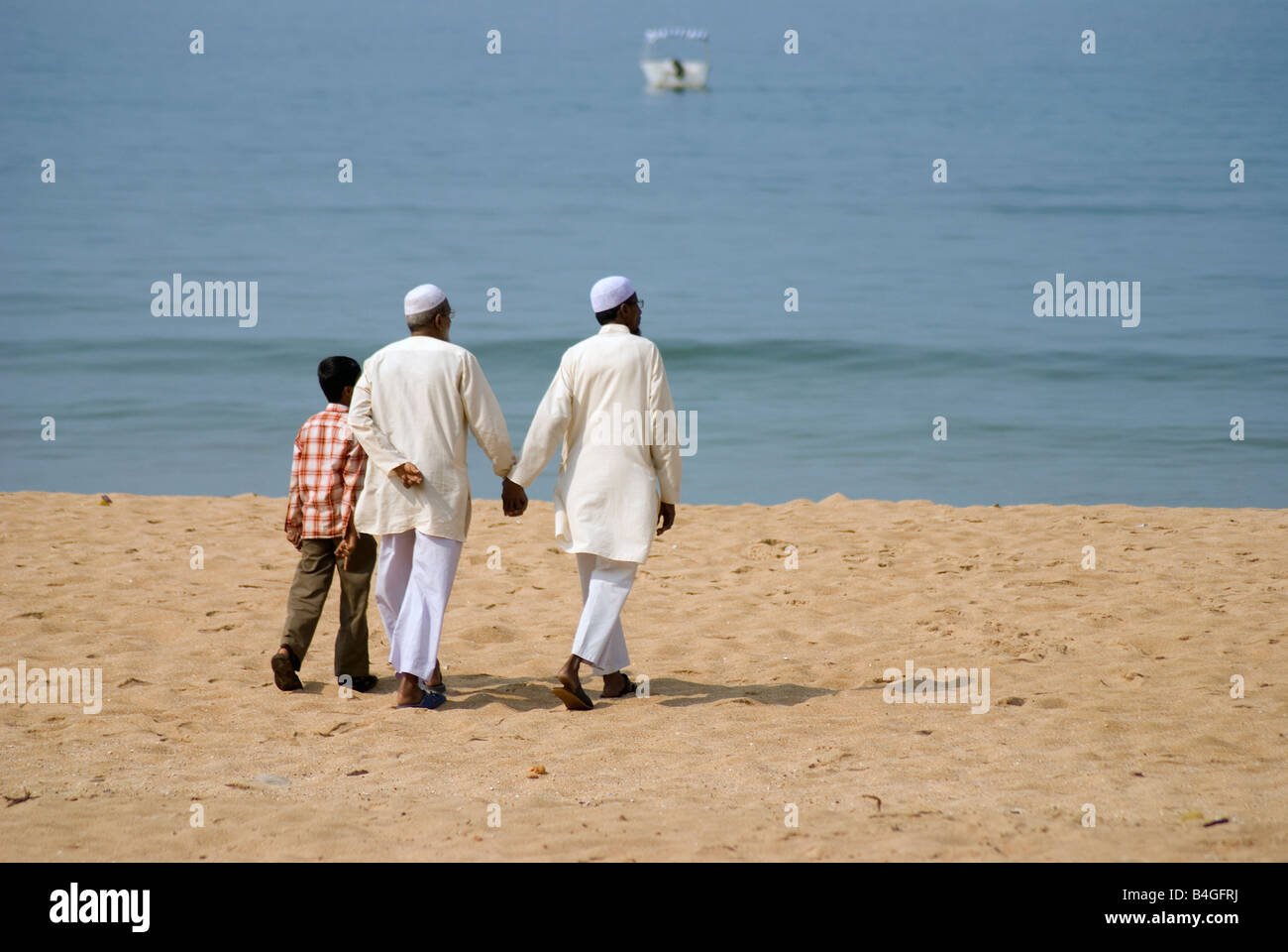 two-muslim-men-and-a-boy-walking-on-the-beach-holding-hands-B4GFRJ.jpg