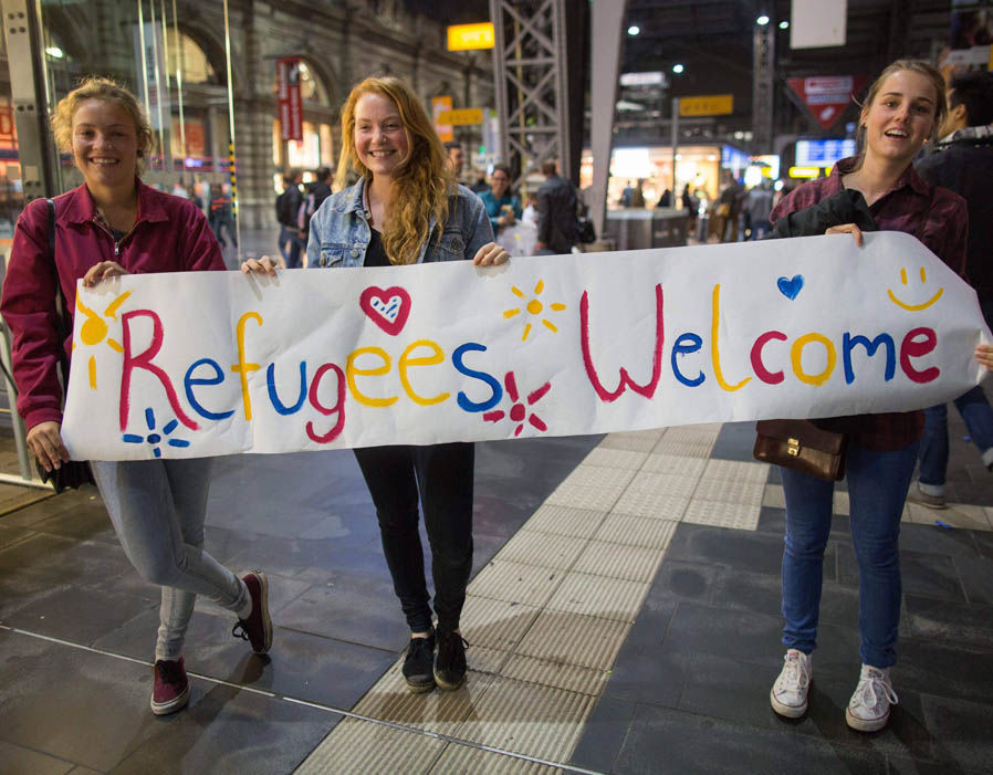 Girls-standing-with-sign-welcoming-migrants-70132.jpg
