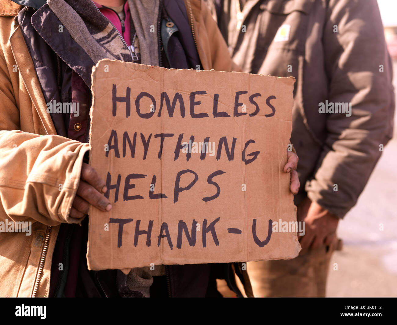 homeless-persons-holding-sign-asking-for-help-and-handouts-unemployed-BK0TT2.jpg