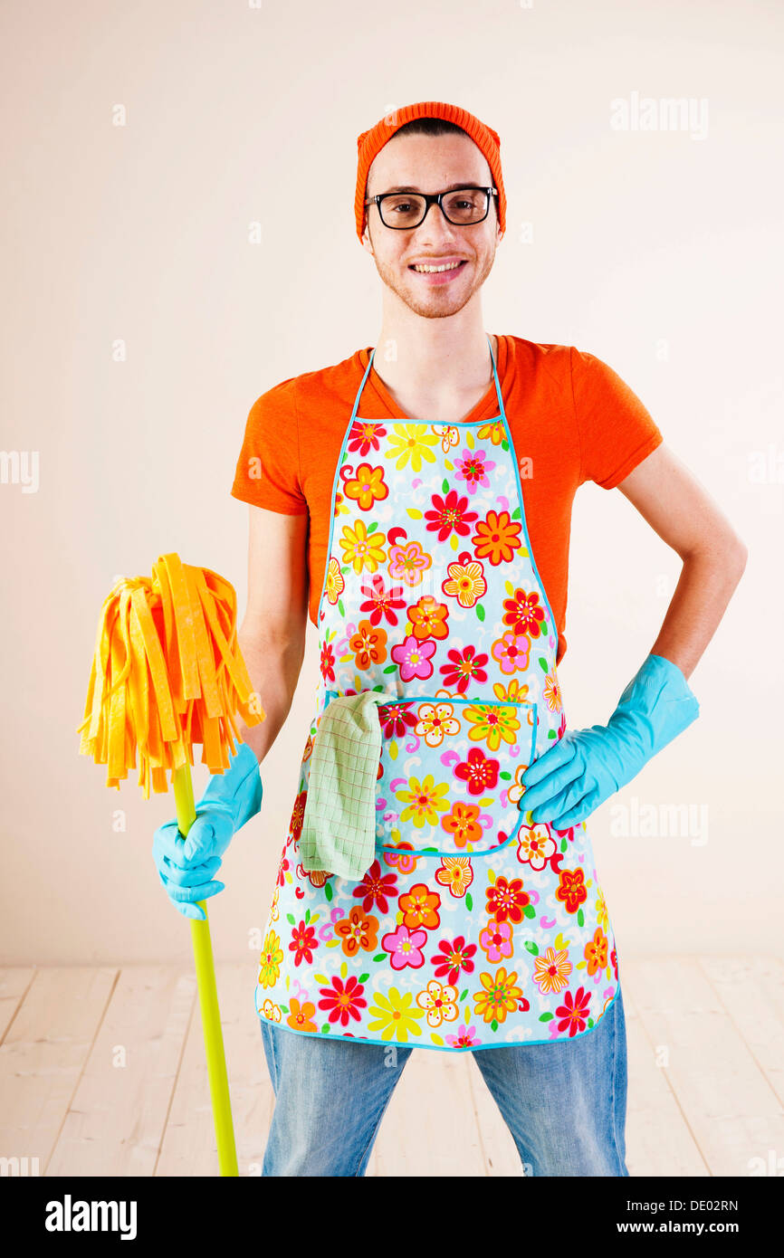 young-man-wearing-an-apron-and-cleaning-gloves-holding-a-cleaning-DE02RN.jpg