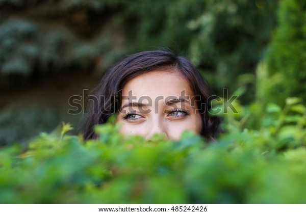 girl-hiding-behind-bush-looks-600w-485242426.jpg