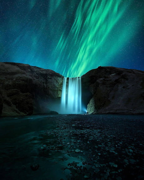 Aurora Borealis painted behind a glowing waterfall in Iceland