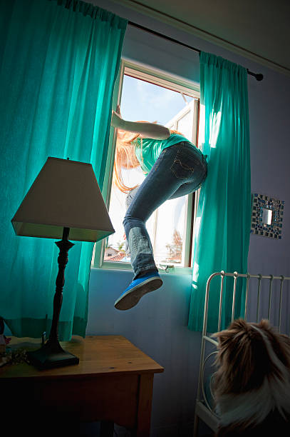 teen-girl-sneaking-out-her-bedroom-window-picture-id180585315