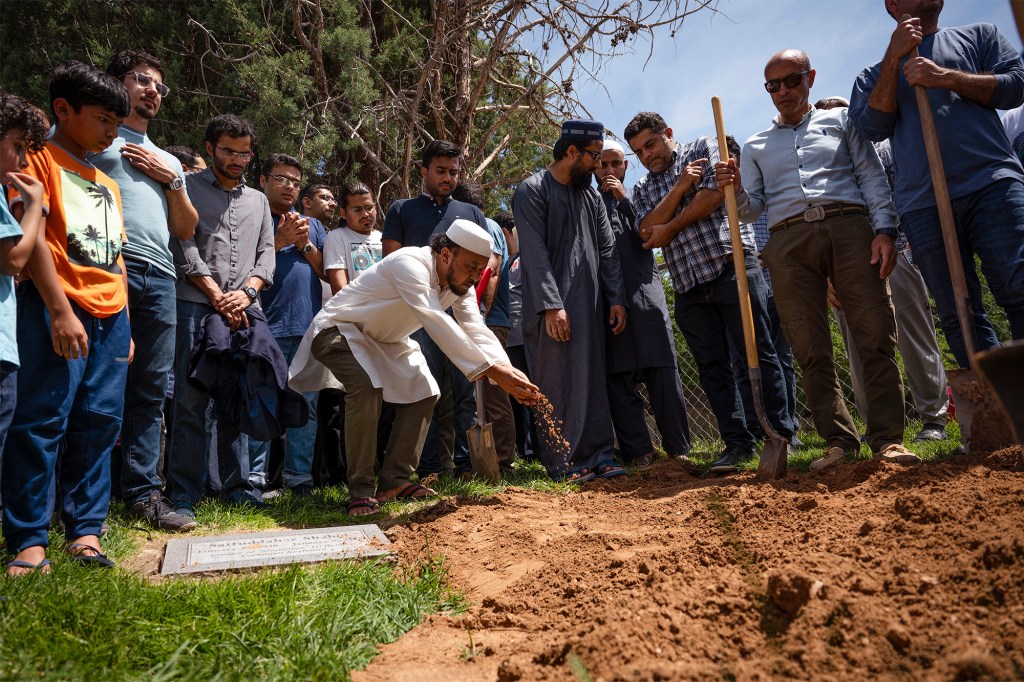 Mourners sprinkle dirt over the grave of Muhammad Afzaal Hussain during his burial at Fairview Memorial Park in Albuquerque, New Mexico on Aug. 5, 2022.