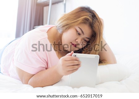 stock-photo-fat-woman-using-smart-phone-and-tablet-on-bed-person-using-digital-tablet-in-living-room-typing-652017019.jpg