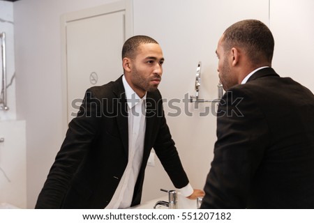 stock-photo-back-view-of-african-man-in-suit-looking-at-mirror-in-bathroom-in-hotel-room-551207182.jpg